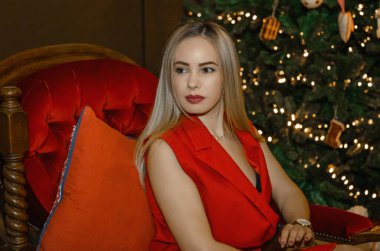 Genç ve mutlu bir kadın Noel ağacı fotoğrafının yanında oturuyor.