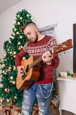 Mutlu çocuk yılbaşı fotoğrafında gitar çalıyor.