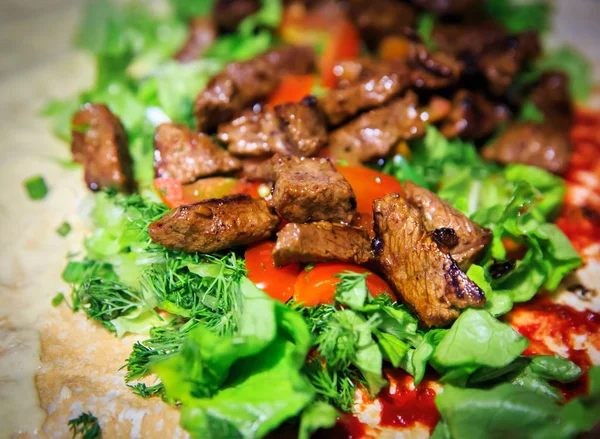 Juicy pieces of grilled meat on green salad with tomatoes — Stock Photo, Image