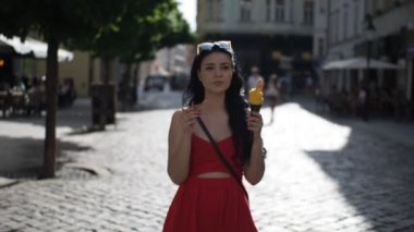 Kırmızı elbiseli genç güzel kadın, Bratislava şehrinin tarihi bir bölgesinde Slow Motion Hd Video 'da yürürken gülümsüyor ve dondurma yiyor. Yarı hız. 