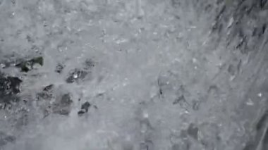 SLOW MOTION HD VIDEO 'daki Woodland' da nehir çağlayanı üzerinde küçük bir şelale. Vadide akan parlak su akıntısı. Su damlaları köpük yapar. Yakın plan. Yarı hız.