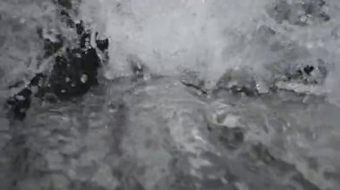 SLOW MOTION HD VIDEO 'daki Woodland' da nehir çağlayanı üzerinde küçük bir şelale. Vadide akan parlak su akıntısı. Su damlaları köpük yapar. Yakın plan. Yarı hız.