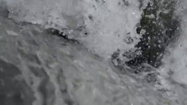 SLOW MOTION HD VIDEO 'daki Woodland' da nehir çağlayanı üzerinde küçük bir şelale. Vadide akan parlak su akıntısı. Su damlaları köpük yapar. Yakın plan. Yarı hız.