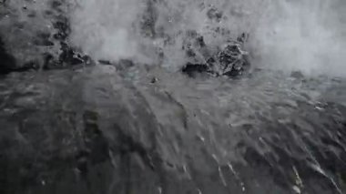 SLOW MOTION HD VIDEO 'daki Woodland' da nehir çağlayanı üzerinde küçük bir şelale. Vadide akan parlak su akıntısı. Su damlaları köpük yapar. Yakın plan. Yarı hız.