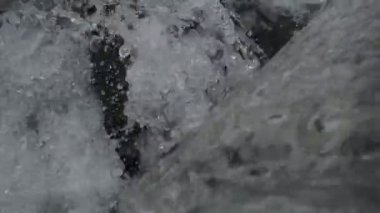 SLOW MOTION HD VIDEO 'daki Woodland' da nehir çağlayanı üzerinde küçük bir şelale. Vadide akan parlak su akıntısı. Su damlaları köpük yapar. Yakın plan. Yarı hız.
