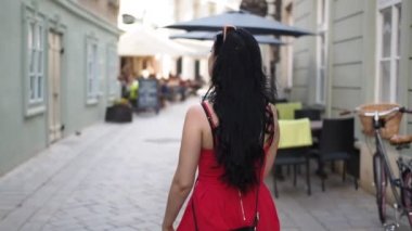 Genç esmer kadın sokakta yürüyor, etrafa bakıyor ve Bratislava şehrinin tarihi kısmında akıllı telefon navigasyonunu kullanıyor. Yavaş Hareket HD VIDEO. Yarı hız, dikiz aynası.
