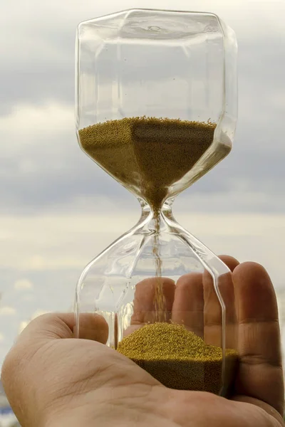 Hourglass in the hands of man. The time of human life. The ratio of humanity and time. The short life of man in the universe.