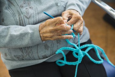 close up of old woman hands with needle blue wool clipart