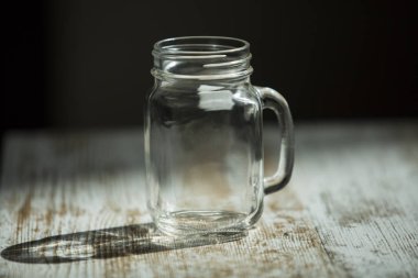 Dağınık ışığı olan bir masada boş bir bardak. 