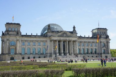 People relaxing on the grass in front of the Reichstag building, seat of the German Parliament (Deutscher Bundestag).