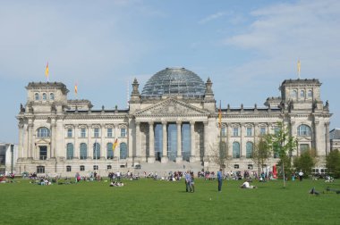 People relaxing on the grass in front of the Reichstag building, seat of the German Parliament (Deutscher Bundestag).
