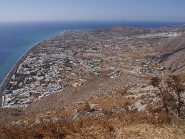 Santorini adasındaki Perissa köyünün panoramik manzarası, dağın tepesinden. Akdeniz ve plajların havadan görünüşü.