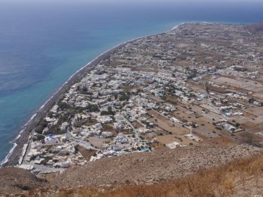 Santorini adasındaki Perissa köyünün panoramik manzarası, dağın tepesinden. Akdeniz ve plajların havadan görünüşü.