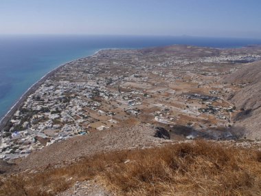 Santorini adasındaki Perissa köyünün panoramik manzarası, dağın tepesinden. Akdeniz ve plajların havadan görünüşü.