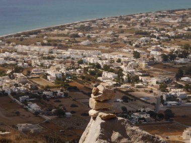 Ege Denizi 'nin arka planındaki taş piramit ve Yunanistan' ın Santorini adasındaki Perissa köyü.