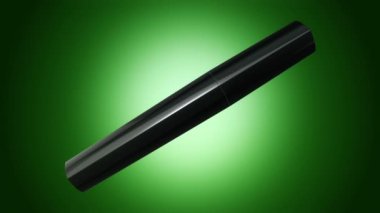 Yeşil arka planda siyah şişede maskara açıp döndürmenin animasyonu, pürüzsüz döngünün animasyonu.