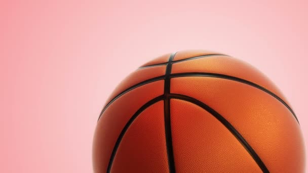 ピンクの背景にリアルな質感と光を持つバスケットボールゲームのための遅い回転オレンジボールのアニメーション シームレスなループ — ストック動画