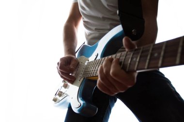 Mavi beyaz elektro gitar çalan bir adamın orta ölçekli görüntüsü.