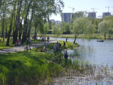 Kiev / Ukraine - April 30, 2018: View of the park with a lake and people relaxing on a sunny spring day.