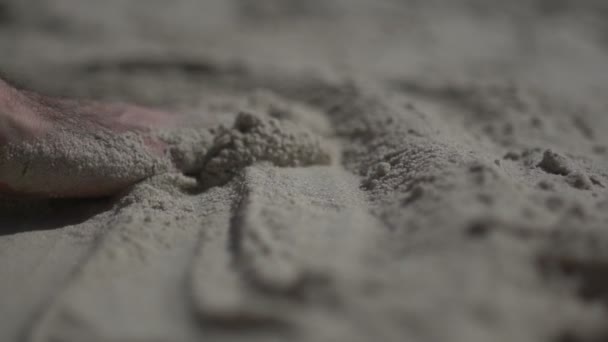 Närbild skott på en man hand vidrör sandstranden. Slow motion verkliga livet — Stockvideo