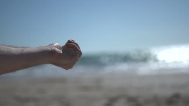 Primer plano tiro en mano de hombre cercano en la playa, la celebración de arena de playa y abrir lentamente — Vídeo de stock