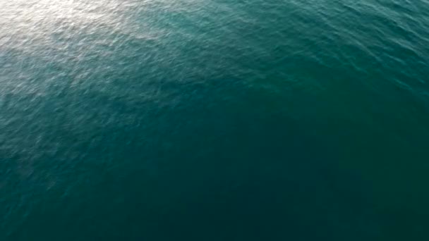 Aerial Over the calm Ocean Water Surface with Blue Sea Ripples And Waves slow movement with ray of sunlight reflection sunbeam — Stock Video