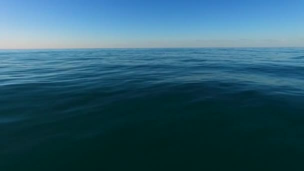 Vuela a baja altitud aérea sobre la superficie del agua del océano con olas y ondulaciones marinas azules. Horizonte vista sin fin — Vídeo de stock