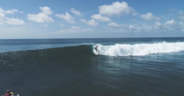 Surfer Légi követés lövés képzett férfi szörfös lovaglás egy hatalmas hullám egy tiszta kék nap az óceán fogás hullámok — Stock videók