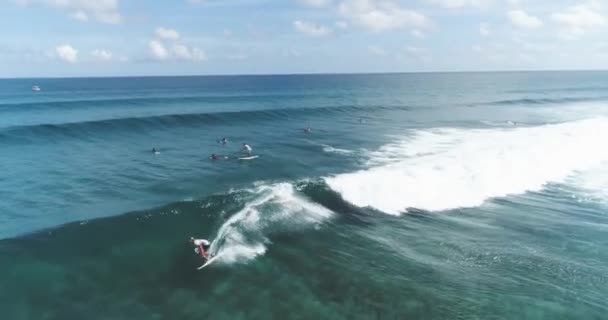 Surfer Lucht tracking schot op geschoolde mannelijke surfer rijden een enorme golf op een heldere blauwe dag op de oceaan vangen golven — Stockvideo