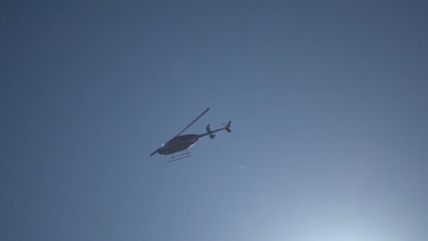 Helikopterhelikopter på blå himmel med ljusstrålar. Slow motion snabb slutartid — Stockvideo