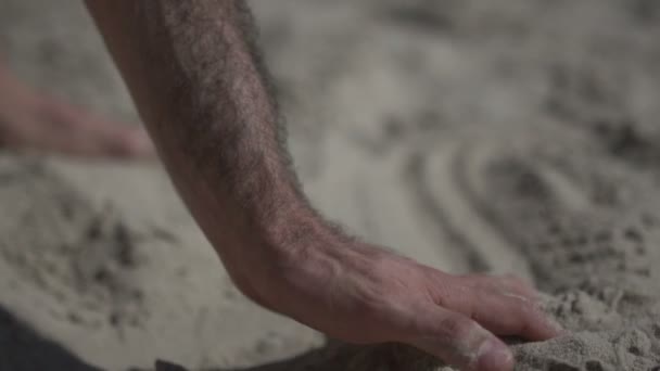 Gros plan sur un homme touchant la plage de sable. Ralenti la vie réelle — Video