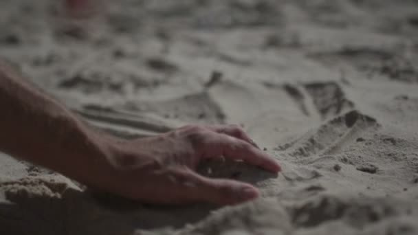 Un colpo ravvicinato sulla mano di un uomo che tocca la spiaggia di sabbia. Rallentatore vita reale — Video Stock