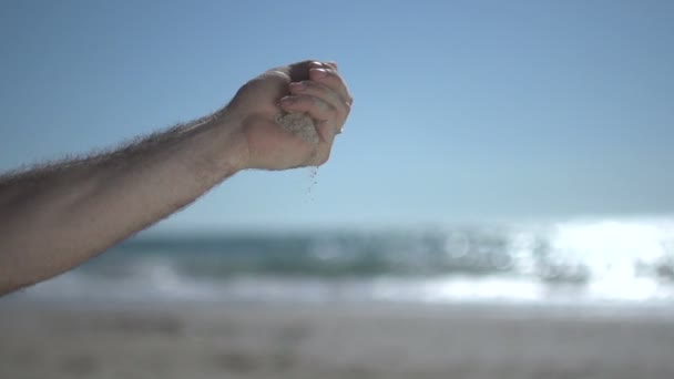 Close up tiro na mão homem próximo na praia, segurando areia da praia e abra lentamente — Vídeo de Stock