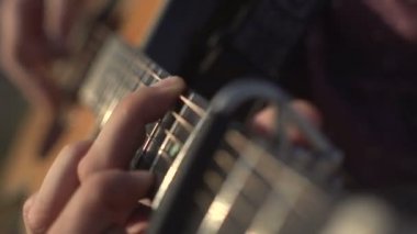 Gitar çalan ve akustik akustik çalan bir adam. Yakın çekim yan açı çekimi açık havada.