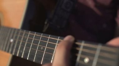 Gitar çalan ve akustik akustik çalan bir adam. Yakın çekim yan açı çekimi açık havada.