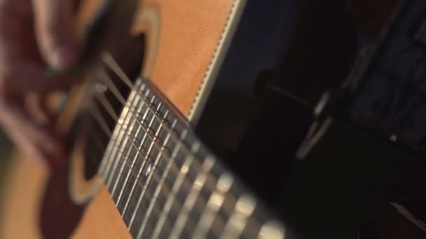 Muž hraje a ladění akustické kytara zavřít záběr boční úhel výstřel venkovní — Stock video