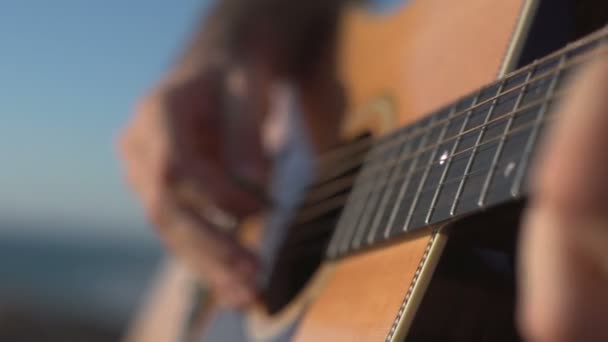 Mann spielt und stimmt Akustikgitarre Nahaufnahme Schuss Seitenwinkelschuss im Freien — Stockvideo