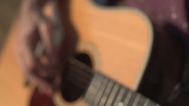 Человек играет и настраивает акустическую гитару Крупный план съемки боковой угол съемки открытый — стоковое видео