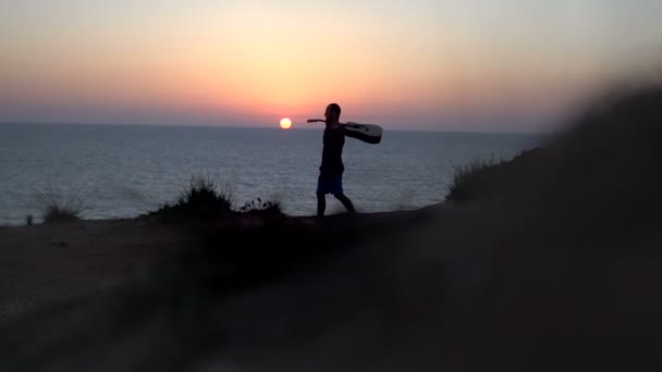 Silhouette fiatal férfi dalírás szabadban játszik akusztikus gitár naplementekor — Stock videók