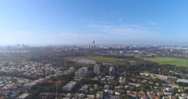 Tel Aviv 'in yeşil silueti manzaralı, yeşil Central Park' ın üzerindeki konut evlerinden yükselen insansız hava aracı ve ufukta deniz manzaralı gökyüzü manzaralı gölet manzaralı.. 