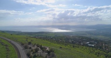 İsrail 'in kuzeyindeki Golan Tepeleri ve Taiberia' nın üzerinde hava görüntüleri. Yeşil manzaralı ve Celile 'nin yukarısındaki dağlarla ya da Ürdün' deki Kinnert vadisiyle yol şeridinde giden araba. 