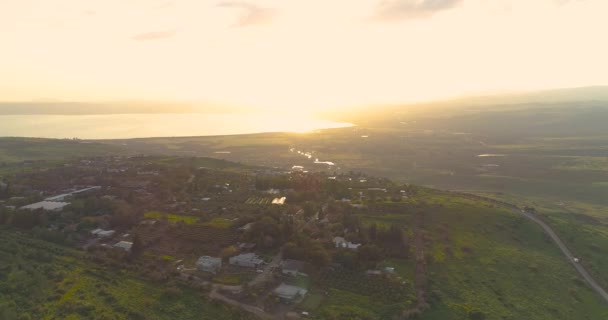 Lanzamiento aéreo al atardecer sobre las alturas del Golán y Taiberia en el norte de Israel. Campos abiertos con paisajes verdes anaranjados y montañas sobre el mar de Galilea o Kinnert en el valle del Jordán — Vídeo de stock