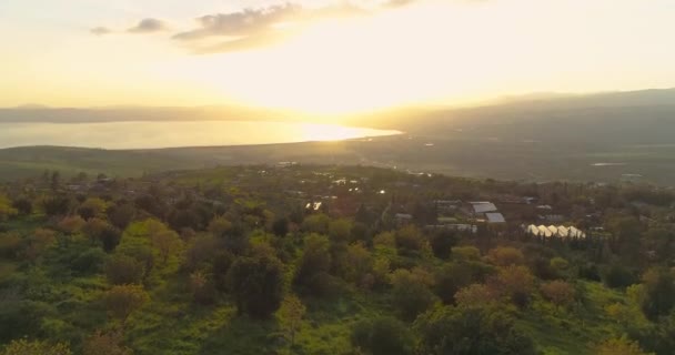Zdjęcia lotnicze o zachodzie słońca nad wzgórzami Golan i Taiberia w północnym Izraelu. Otwarte pola z pomarańczowymi zielonymi krajobrazami i górami nad morzem Galilejskim lub Kinnert w dolinie Jordanu — Wideo stockowe