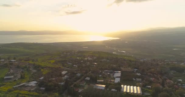 Luchtfoto bij zonsondergang boven Golan Heights en Taiberia in het noorden van Israël. Open velden met oranje groene landschappen en bergen boven Galilea zee of Kinnert in Jordanië vallei — Stockvideo