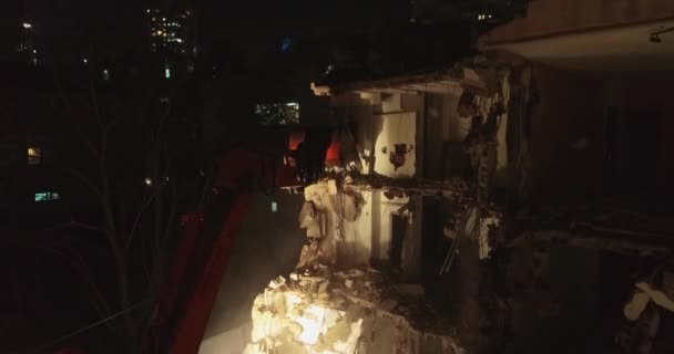 Escavadeira destruindo parede de concreto. Tiro aéreo acima. Escavadeira destruindo e demolir antiga casa de apartamentos no centro da cidade à noite . — Vídeo de Stock