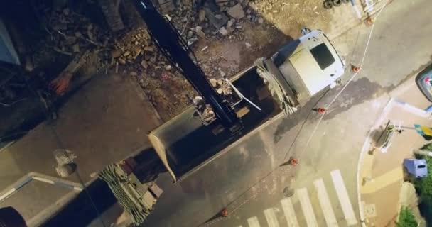 La machine d'excavation charge les débris et la saleté des constructions lourdes dans un camion à benne dans la ville la nuit 