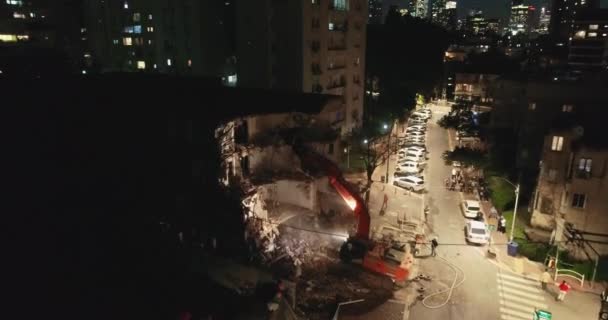 Ο εκσκαφέας καταστρέφει το τσιμεντένιο τείχος. Αεροπλάνο από πάνω. Ο εκσκαφέας καταστρέφει και κατεδαφίζει παλιά πολυκατοικία στο κέντρο της πόλης τη νύχτα. — Αρχείο Βίντεο