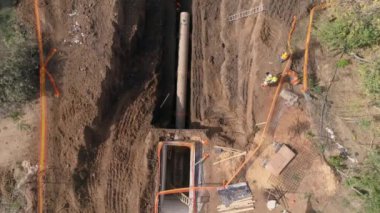 İnşaat alanının yukarısındaki havadan aşağıya, işçilerin ve kazıcıların çalıştığı ve büyük beton boru hatlarıyla işlenmemiş kum zemininde kazı yaptığı yer. 