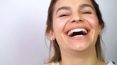 Çekici melez kadın gülüyor ve kameraya bakıyor. Güzel dişler, gözler ve dudaklar. Beyaz arkaplanda yakın plan portresi.