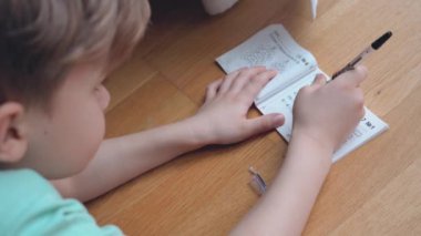 Çocuk konsantre oluyor ve düşünüyor. Çocuk ödevlerini yapıyor ve defterine yazı yazıyor. Matematik yapıyorum..